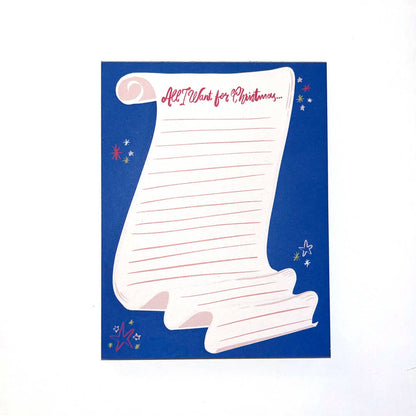 A notepad with an illustration of a scroll of lined paper with the words "All I Want for Christmas" written across the top.