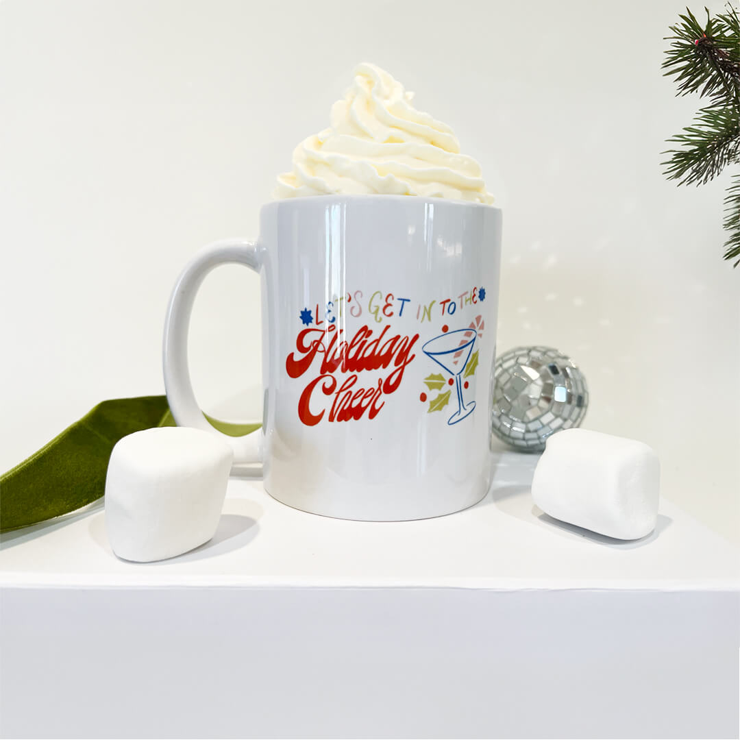 Ceramic mug with "Let's Get into the Holiday Cheer" designed across it.